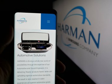 Stuttgart, Almanya - 06-11-2025: Logo önünde ekranda Harman International Industries Inc. şirketinin web sayfası ile akıllı telefon tutan kişi. Telefon ekranının merkezine odaklan.