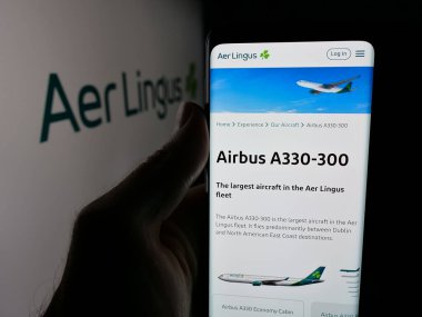 Stuttgart, Almanya - 06-11-2025: İrlandalı havayolu şirketi Aer Lingus 'un internet sayfası ile cep telefonu tutan kişi logonun önünde ekranda. Telefon ekranının merkezine odaklan.
