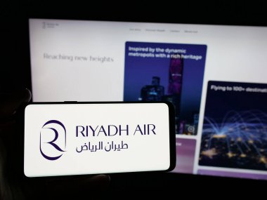 Stuttgart, Almanya - 06-13-2025: Suudi Arabistan havayolu şirketi Riyad Air 'in logosunu taşıyan kişi web sitesinin önünde ekranda. Telefon ekranına odaklan.