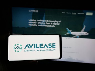 Stuttgart, Almanya - 06-13-2025: Suudi uçak kiralama şirketi AviLease 'in logosuna sahip akıllı telefon sahibi kişi web sitesinin önünde ekranda. Telefon ekranına odaklan.