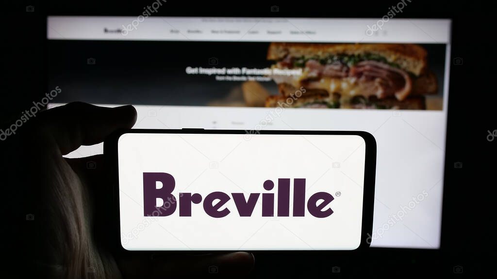 Stuttgart, Germany - 06-12-2025: Person holding cellphone with logo of home appliances company Breville Group Ltd. on screen in front of webpage. Focus on phone display.