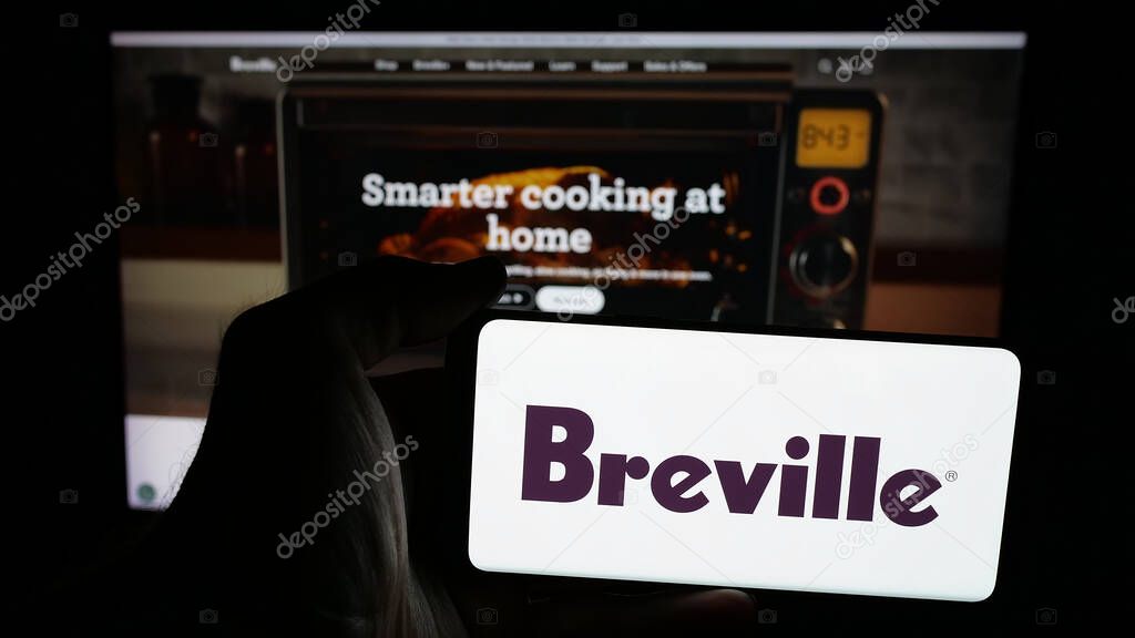 Stuttgart, Germany - 06-12-2025: Person holding mobile phone with logo of home appliances company Breville Group Ltd. on screen in front of web page. Focus on phone display.
