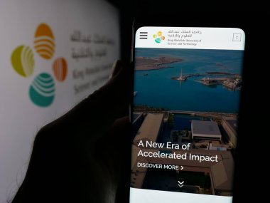 Stuttgart, Almanya - 06-14-2025: Suudi Kral Abdullah Üniversitesi 'nin (KAOD) web sayfası logonun önünde duran kişi. Telefon ekranının merkezine odaklan.