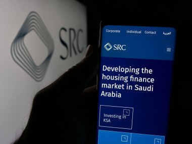 Stuttgart, Almanya - 06-14-2025: Logo önündeki ekranda Suudi Gayrimenkul Koruma Şirketi 'nin (SRC) web sayfası bulunan kişi. Telefon ekranının merkezine odaklan.