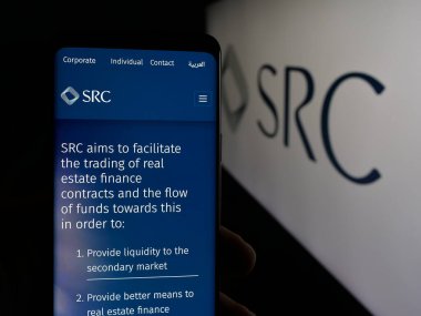 Stuttgart, Almanya - 06-14-2025: Logo önündeki ekranda Suudi Emlak Yenileme Şirketi 'nin (SRC) web sayfası olan akıllı telefon sahibi kişi. Telefon ekranının merkezine odaklan.