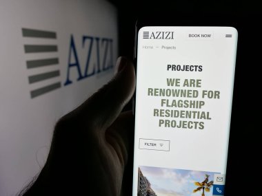 Stuttgart, Almanya - 06-18-2025: UAE geliştirme şirketi Azizi Developments 'ın web sayfası olan akıllı telefon sahibi kişi logonun önünde ekranda. Telefon ekranının merkezine odaklan.