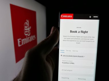 Stuttgart, Almanya - 06-18-2025: UAE havayolu şirketi Emirates 'in web sayfası olan cep telefonu logosu önünde ekranda. Telefon ekranının merkezine odaklan.
