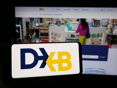 Stuttgart, Almanya - 06-18-2025: İnternet sitesi önünde üzerinde BAE havaalanı yetkilisi Dubai Havaalanı Şirketi logosu bulunan akıllı telefon sahibi kişi. Telefon ekranına odaklan.