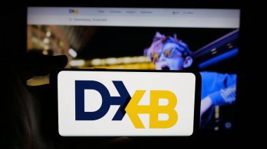 Stuttgart, Almanya - 06-18-2025: BAE havaalanı yetkilisi Dubai Havaalanı Şirketi 'nin logosunun bulunduğu cep telefonu sahibi kişi web sitesinin önünde ekranda. Telefon ekranına odaklan.