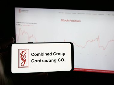 Stuttgart, Almanya - 06-18-2025: İnternet sitesi önünde üzerinde Birleşik Grup Müteahhitlik Şirketi (CGC) logosu bulunan akıllı telefon sahibi kişi. Telefon ekranına odaklan.