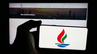 Stuttgart, Almanya - 06-18-2025: İnternet sayfası önünde üzerinde Kuveyt Ulusal Petrol Şirketi (KNPC) logosu bulunan cep telefonu sahibi kişi. Telefon ekranına odaklan.