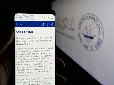 Stuttgart, Almanya - 06-19-2025: Kuveyt Merkez Bankası (CBK) kurumunun web sayfası logonun önünde duran kişi. Telefon ekranının merkezine odaklan.