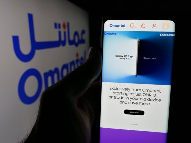 Stuttgart, Almanya - 06-20-2025: Umman Telekomünikasyon Şirketi 'nin (Omantel) web sayfası logonun önünde cep telefonu tutan kişi. Telefon ekranının merkezine odaklan.