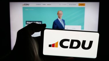 Stuttgart, Almanya - 06-25-2025: İnternet sayfası önünde üzerinde parti Christlich Demokratische Union (CDU) logosu bulunan cep telefonu sahibi kişi. Telefon ekranına odaklan.