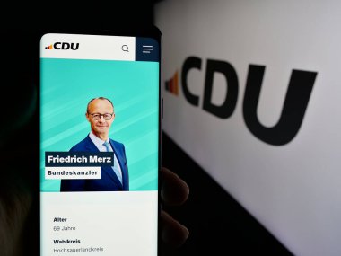 Stuttgart, Almanya - 06-25-2025: Parti Christlich Demokratische Union 'un (CDU) web sayfası logo önünde ekranda olan cep telefonu sahibi kişi. Telefon ekranının merkezine odaklan.