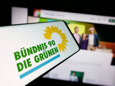 Stuttgart, Almanya - 06-25-2025: İnternet sitesi önünde Alman partisi Buendnis 90 Die Gruenen 'in (Yeşiller) logosuna sahip akıllı telefon. Telefon ekranının merkezine odaklan.