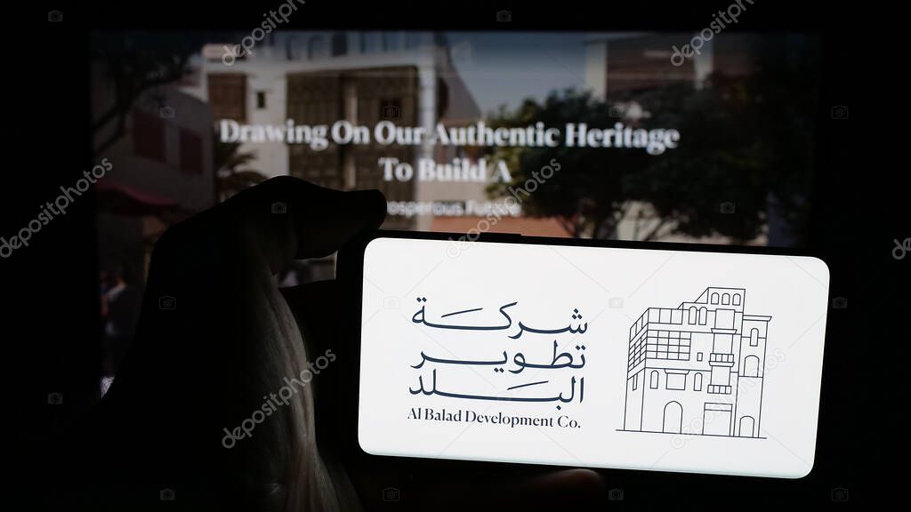 Stuttgart, Germany - 06-14-2025: Person holding mobile phone with logo of business Al Balad Development Company (BDC) on screen in front of web page. Focus on phone display.
