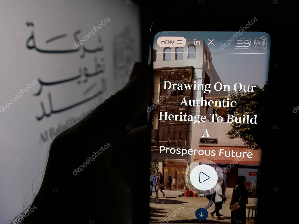 Stuttgart, Germany - 06-14-2025: Person holding cellphone with webpage of business Al Balad Development Company (BDC) on screen in front of logo. Focus on center of phone display.