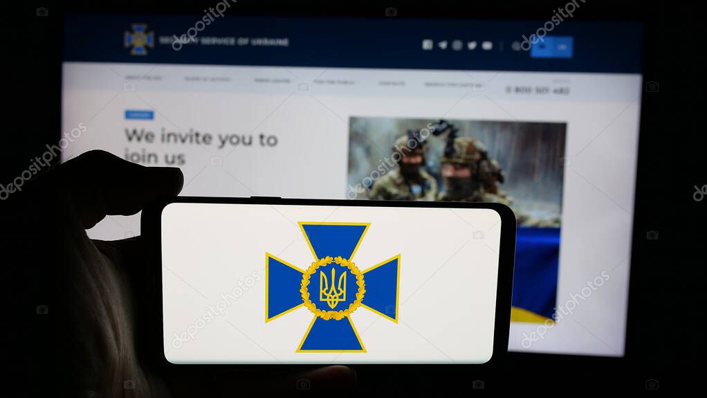 Stuttgart, Germany - 06-18-2025: Person holding cellphone with logo of security service Sluzhba Bezpeky Ukrainy SBU on screen in front of webpage. Focus on phone display.