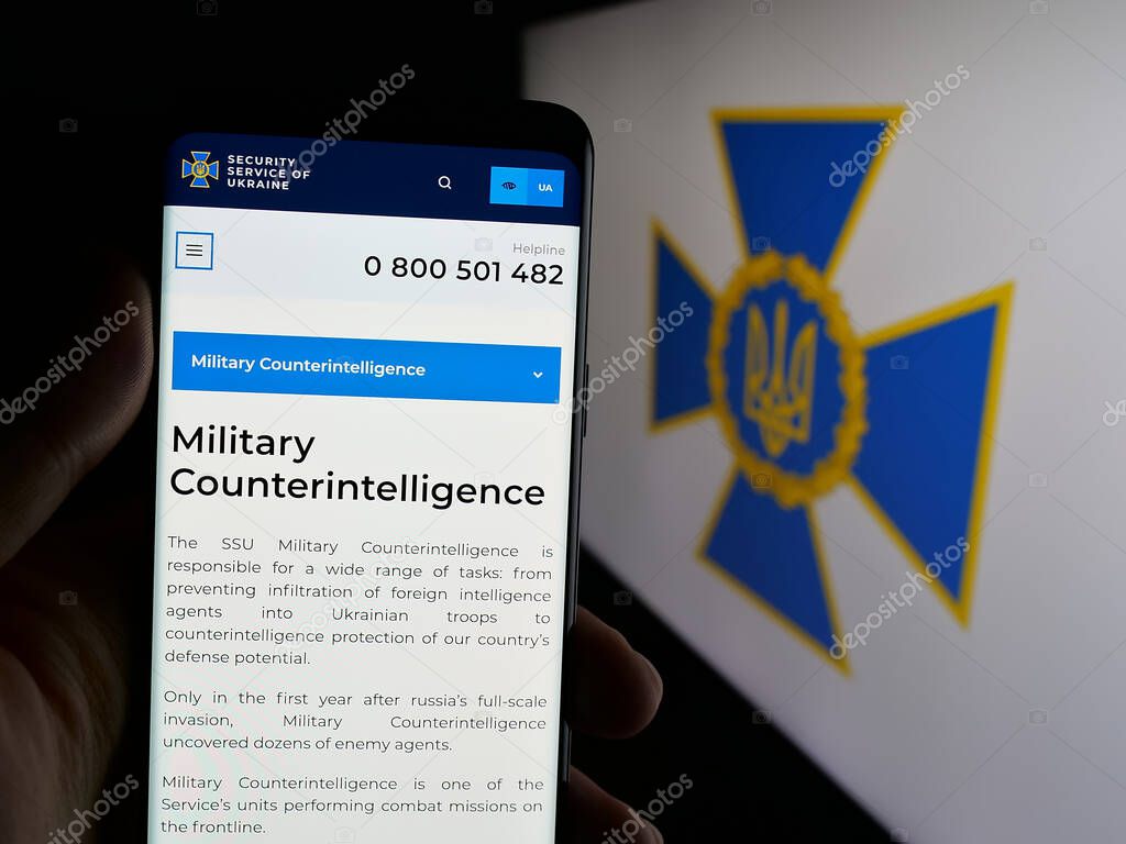 Stuttgart, Germany - 06-18-2025: Person holding smartphone with web page of security service Sluzhba Bezpeky Ukrainy SBU on screen in front of logo. Focus on center of phone display.
