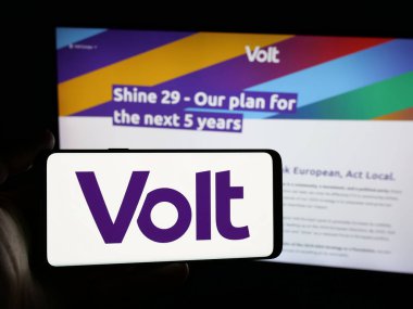 Stuttgart, Almanya - 06-26-2025: İnternet sitesi önünde Avrupa siyasi partisi Volt Europa 'nın logosuna sahip akıllı telefon sahibi kişi. Telefon ekranına odaklan.