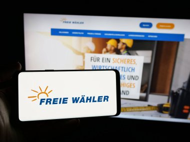Stuttgart, Almanya - 06-26-2025: Alman siyasi partisi Freie Wahler 'in logosunu elinde tutan kişi web sitesinin önünde ekranda. Telefon ekranına odaklan.