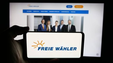 Stuttgart, Almanya - 06-26-2025: Alman siyasi partisi Freie Wahler 'in logosunun bulunduğu cep telefonu web sayfası önünde ekranda. Telefon ekranına odaklan.