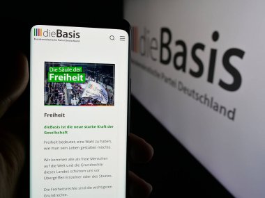 Stuttgart, Almanya - 06-26-2025: Logo önünde Alman Basisdemokratische Partei 'nin (dieBasis) web sayfası bulunan cep telefonu sahibi. Telefon ekranının merkezine odaklan.