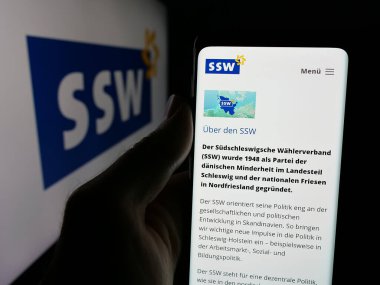 Stuttgart, Almanya - 06-26-2025: Logo önündeki ekranda Alman Suedschleswigscher Waehlerverband 'in (SSW) web sayfası bulunan kişi. Telefon ekranının merkezine odaklan.