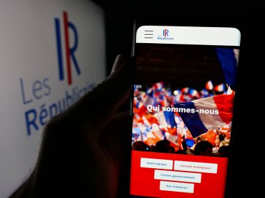 Stuttgart, Almanya - 06-26-2025: Fransız siyasi partisi Les Republicains 'in (LR) web sayfası logonun önünde duran kişi. Telefon ekranının merkezine odaklan.