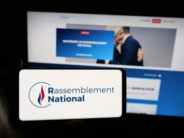 Stuttgart, Almanya - 06-26-2025: İnternet sitesi önünde üzerinde Fransız partisi Rassemblement National (RN) logosu bulunan kişi. Telefon ekranına odaklan.