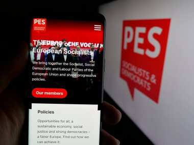 Stuttgart, Almanya - 06-27-2025: Avrupa Sosyalist Partisi (PES) web sitesi logonun önünde cep telefonu tutan kişi. Telefon ekranının merkezine odaklan.