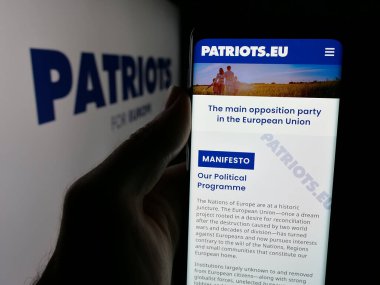 Stuttgart, Almanya - 06-27-2025: Avrupa 'daki siyasi parti Patriots.eu' nun web sayfasını elinde tutan kişi logonun önünde ekranda. Telefon ekranının merkezine odaklan.