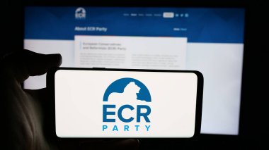 Stuttgart, Almanya - 06-27-2025: Web sayfası önünde AB Muhafazakârları ve Reformcuları Partisi 'nin (AİHM) logosunu elinde tutan kişi. Telefon ekranına odaklan.