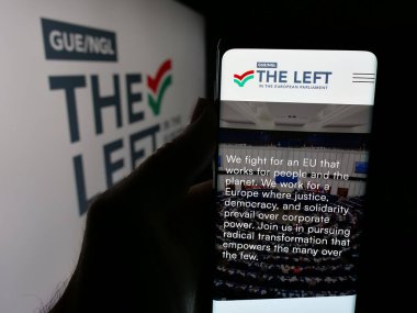 Stuttgart, Almanya - 07-07-2025: Avrupa Parlamentosu 'nda Soldaki web sayfası logonun önünde duran kişi. Telefon ekranının merkezine odaklan.