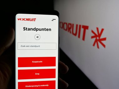 Stuttgart, Almanya - 07-10-2025: Flaman siyasi partisi Vooruit 'in internet sayfası logonun önünde duran kişi. Telefon ekranının merkezine odaklan.