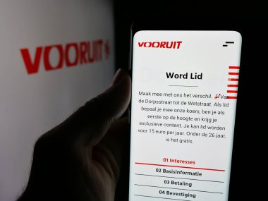 Stuttgart, Almanya - 07-10-2025: Flaman siyasi partisi Vooruit 'in web sayfası logonun önünde duran kişi. Telefon ekranının merkezine odaklan.