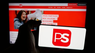 Stuttgart, Almanya - 07-10-2025: İnternet sayfası önünde Belçika 'nın siyasi partisi Parti Socialiste' nin (PS) logosunu elinde tutan kişi. Telefon ekranına odaklan.