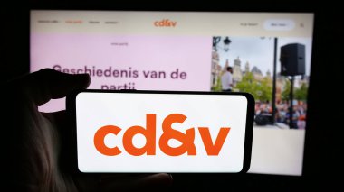 Stuttgart, Almanya - 07-10-2025: Web sayfası önünde üzerinde parti Christen-Democratisch en Vlaams (CDV) logosu bulunan kişi. Telefon ekranına odaklan.
