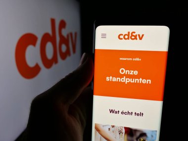 Stuttgart, Almanya - 07-10-2025: Christen-Democratisch en Vlaams (CDV) partisinin web sayfası logonun önünde bulunan kişi. Telefon ekranının merkezine odaklan.
