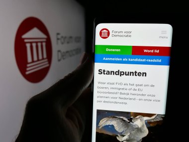 Stuttgart, Almanya - 07-10-2025: Hollandalı parti Forum Voor Democratie 'nin (FvD) web sayfası logonun önünde duran kişi. Telefon ekranının merkezine odaklan.