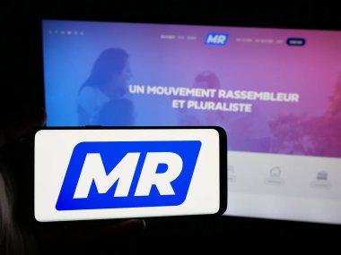 Stuttgart, Almanya - 07-10-2025: İnternet sitesi önünde üzerinde Belçika partisi Mouvement Reformatör (MR) logosu bulunan kişi. Telefon ekranına odaklan.