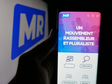 Stuttgart, Almanya - 07-10-2025: Belçika partisi Mouvement Reformatör 'ün (MR) web sayfası logonun önünde duran kişi. Telefon ekranının merkezine odaklan.