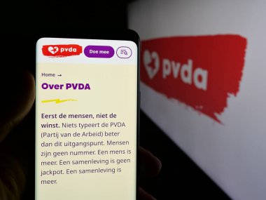 Stuttgart, Almanya - 07-10-2025: Parj van de Arbeid van Belgie 'nin (PVDA) web sayfası logonun önünde duran kişi. Telefon ekranının merkezine odaklan.