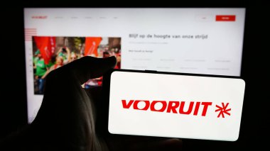 Stuttgart, Almanya - 07-10-2025: Flaman siyasi partisi Vooruit 'in logosunu web sayfasının önünde tutan kişi. Telefon ekranına odaklan.