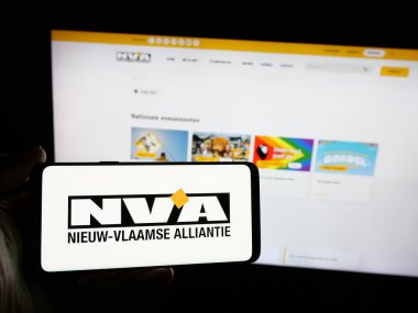 Stuttgart, Almanya - 07-10-2025: İnternet sitesi önünde üzerinde Nieuw-Vlaamse Alliantie (N-VA) logosu bulunan kişi. Telefon ekranına odaklan.