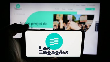 Stuttgart, Almanya - 07-11-2025: İnternet sayfası önünde Belçika siyasi partisi Les Engages 'in (LE) logosunu elinde tutan kişi. Telefon ekranına odaklan.