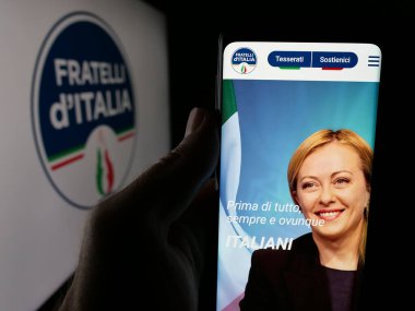 Stuttgart, Almanya - 07-11-2025: İtalyan partisi Fratelli d 'Italia' nın (FDL) web sayfası logonun önünde duran kişi. Telefon ekranının merkezine odaklan.