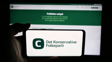 Stuttgart, Almanya - 07-11-2025: İnternet sayfası önünde Danimarka partisi Dedektif Konservatif Folkeparti 'nin (KF) logosunun bulunduğu cep telefonu sahibi kişi. Telefon ekranına odaklan.