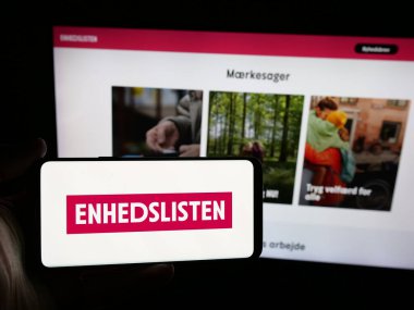 Stuttgart, Almanya - 07-11-2025: Danimarkalı parti Enhedslisten logolu akıllı telefon sahibi kişi web sitesinin önünde ekranda De Rod-Gronne EL. Telefon ekranına odaklan.